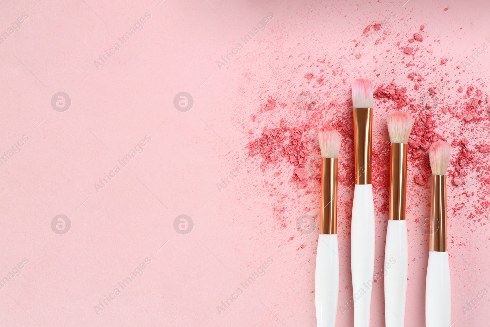 Photo of Makeup brushes and scattered eye shadow on pink background, flat lay. Space for text