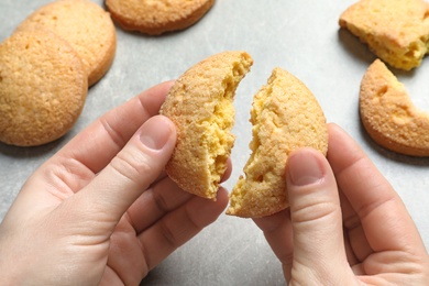 Photo of Woman holding broken Danish butter cookies above table, closeup