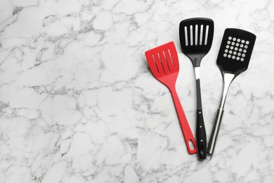 Photo of Clean spatulas on marble background, flat lay. Space for text