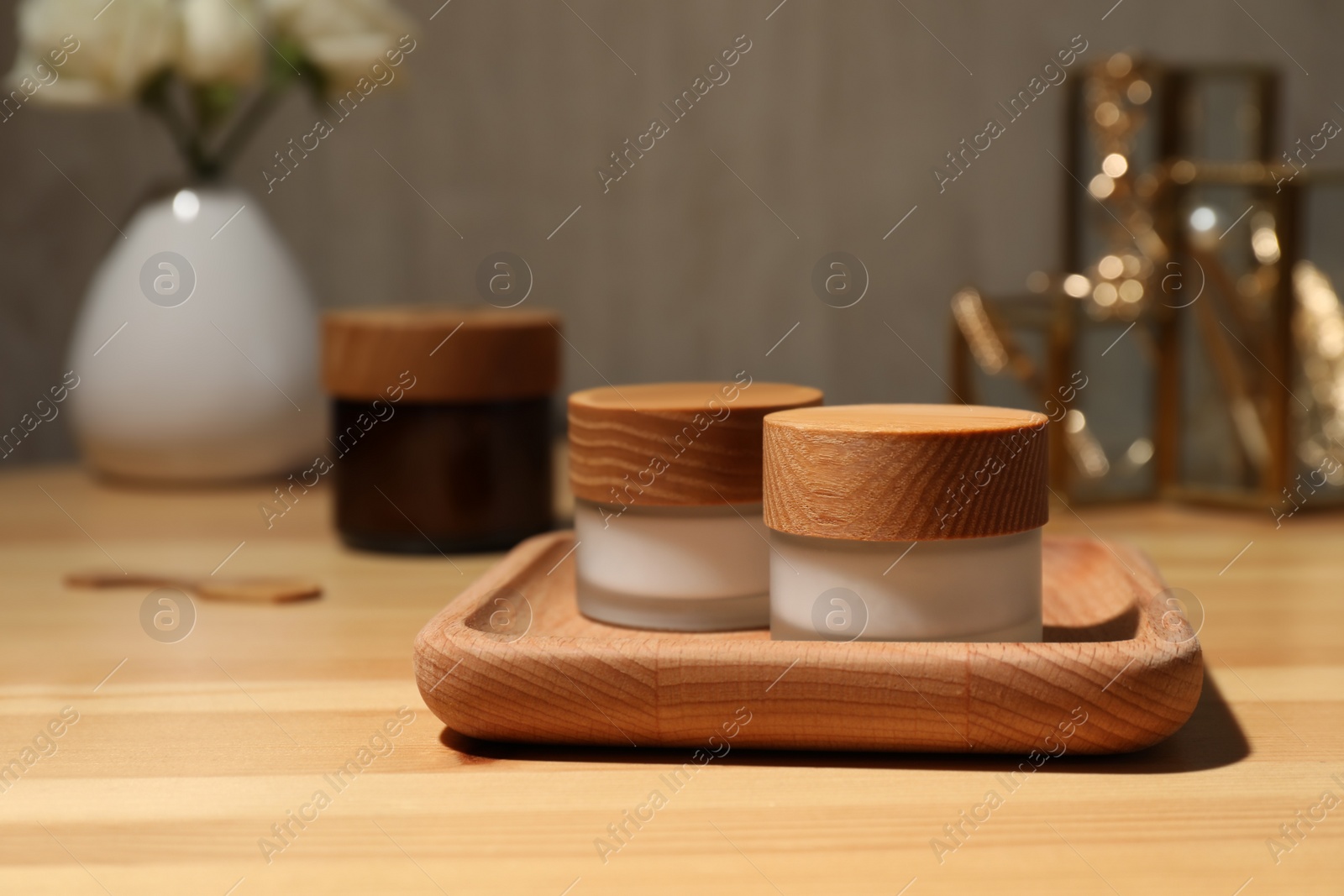 Photo of Jars of cream and tray on wooden table, space for text