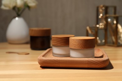 Photo of Jars of cream and tray on wooden table, space for text