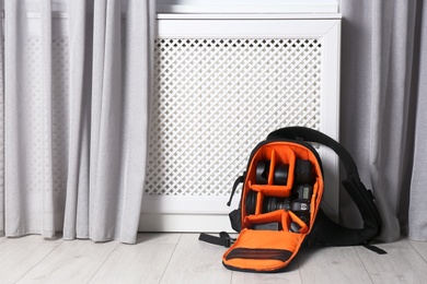 Photo of Bag with digital camera on floor indoors. Professional photographer's equipment