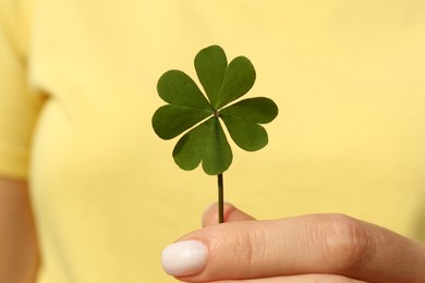 Photo of Woman holding green four leaf clover, closeup