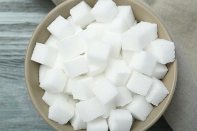 White sugar cubes in bowl on wooden table, top view