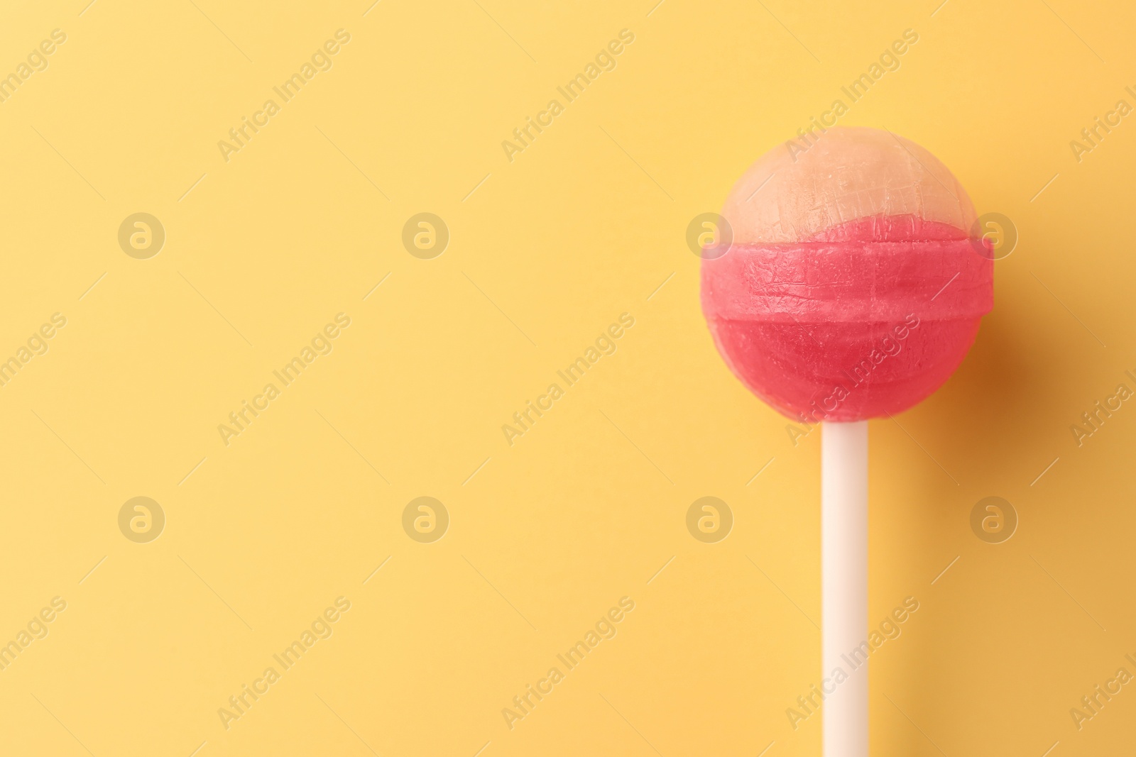 Photo of One tasty lollipop on yellow background, top view. Space for text