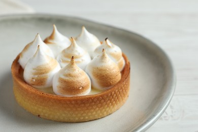 Photo of Tartlet with meringue on white wooden table, closeup and space for text. Delicious dessert