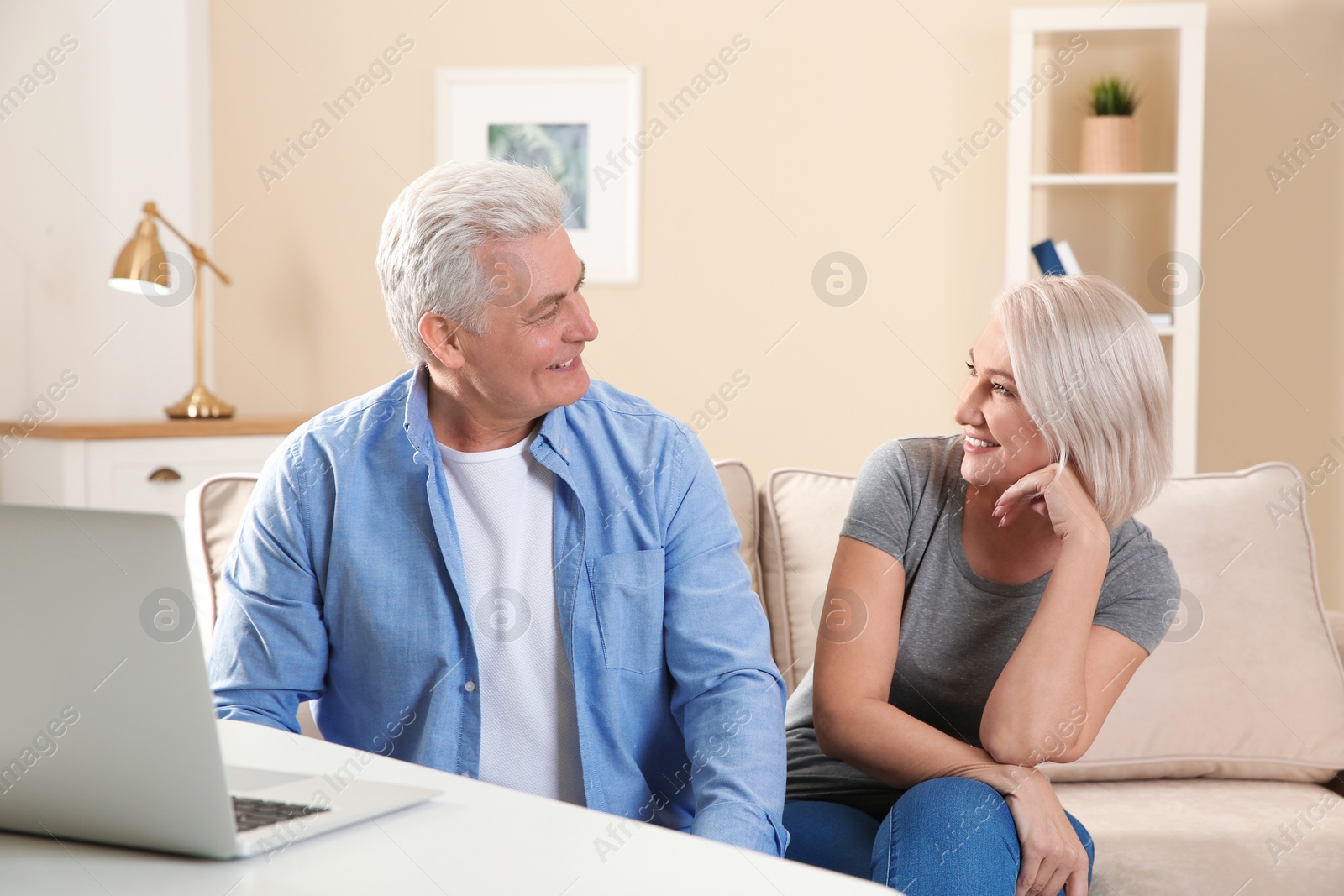 Photo of Mature couple using video chat on laptop at home