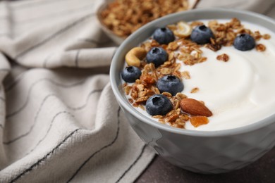 Photo of Bowl with yogurt, blueberries and granola on grey table, closeup