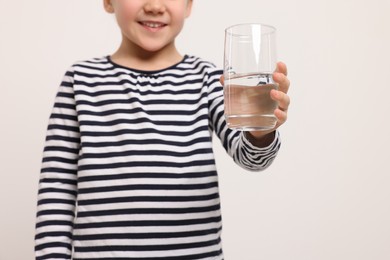Photo of Little girl holding glass of fresh water on white background, closeup. Space for text
