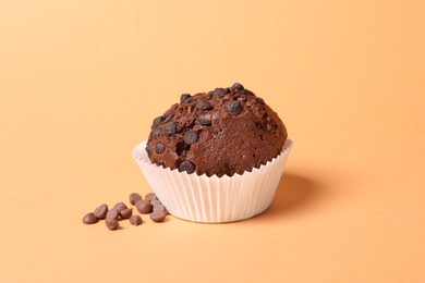 One tasty chocolate muffin on pale orange background