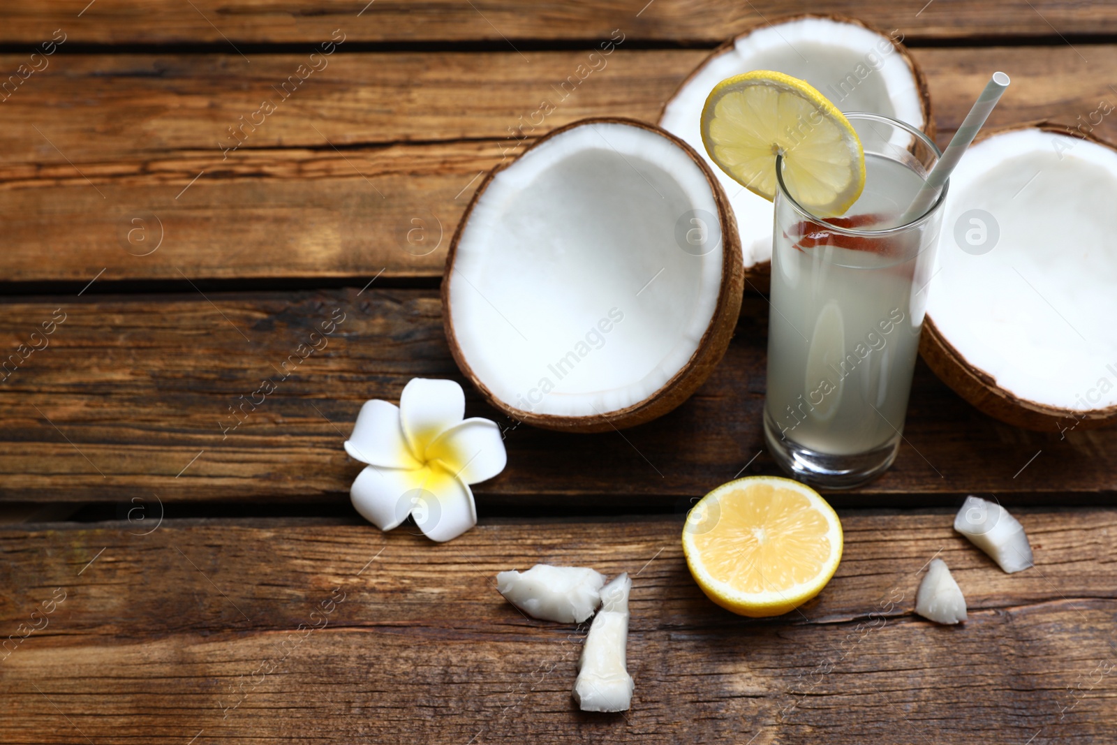 Photo of Composition with glass of coconut water and lemon on wooden table. Space for text