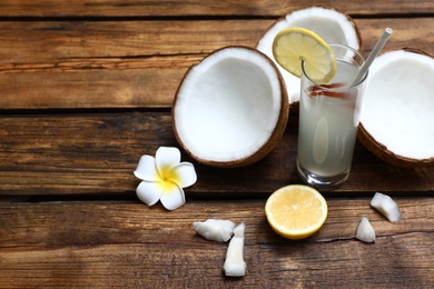 Composition with glass of coconut water and lemon on wooden table. Space for text