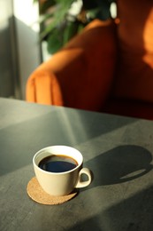 Cup of delicious coffee on grey table indoors. Space for text