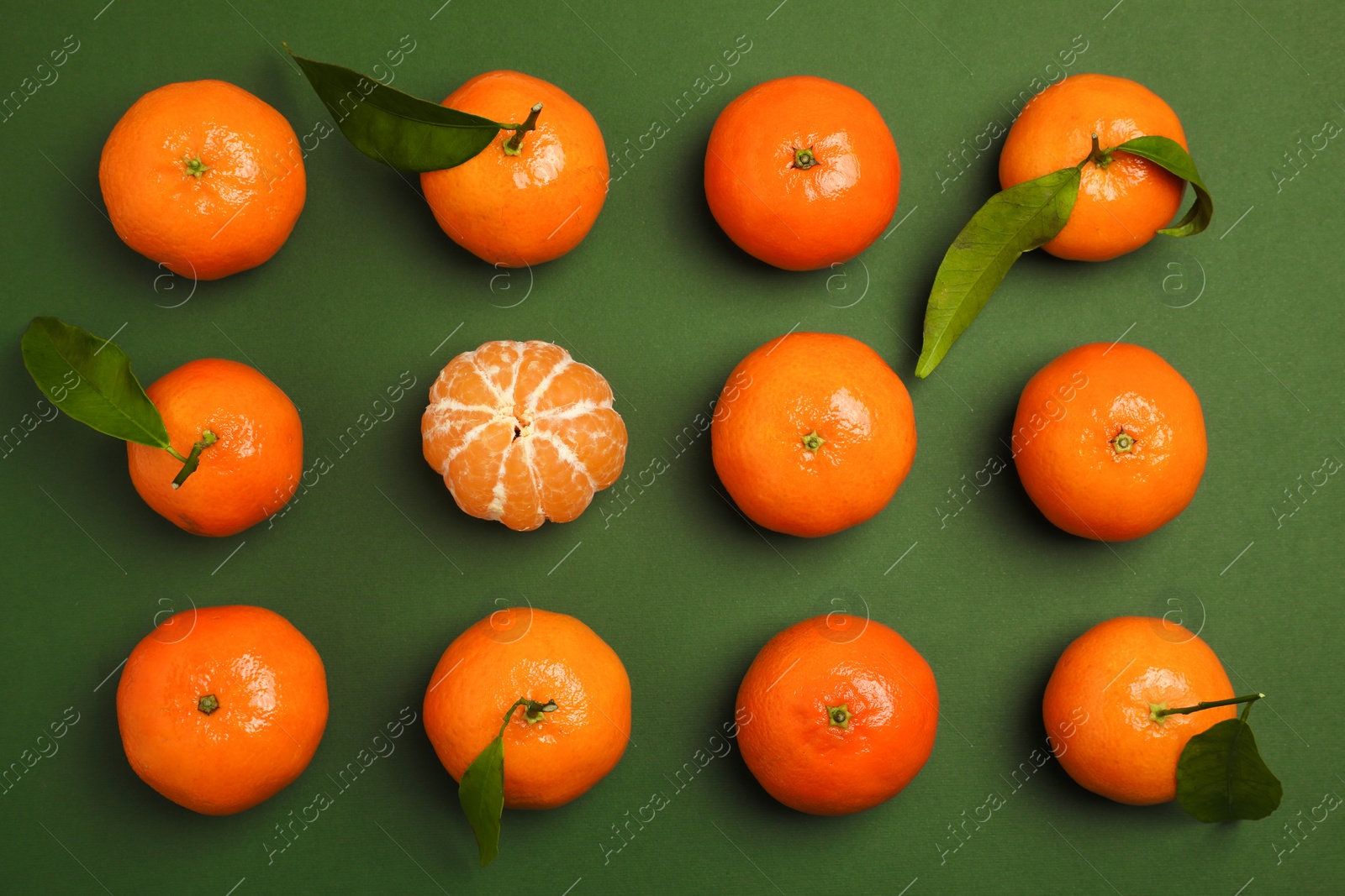 Photo of Delicious tangerines and leaves on green background, flat lay