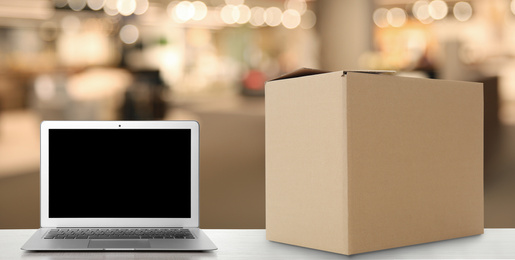 Image of Online selling. Laptop and parcel on table in store, banner design
