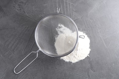 Metal sieve and flour on grey table, top view