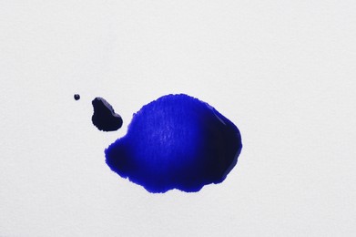 Blot of blue ink on white background, top view