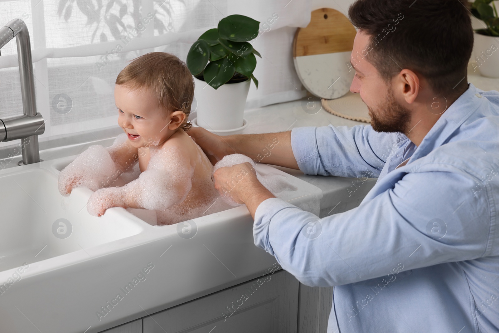 Photo of Father washing his little baby in sink at home