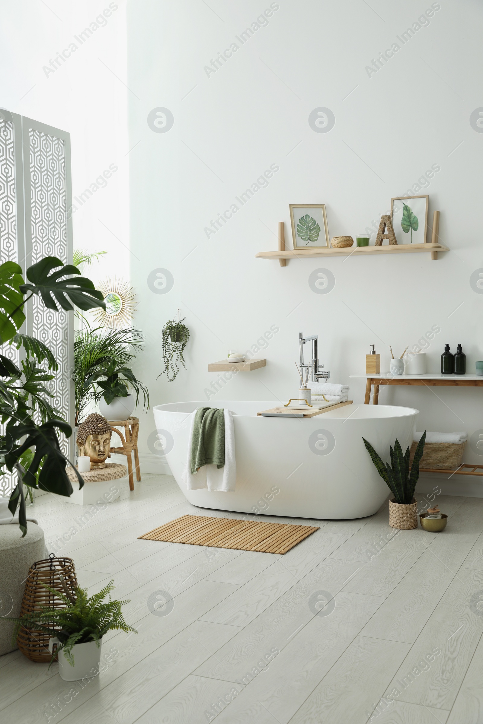 Photo of Stylish bathroom interior with modern tub, houseplants and beautiful decor. Home design