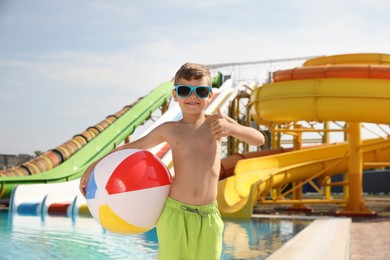 Photo of Cute little boy with inflatable ball near pool in water park