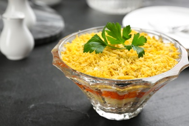 Photo of Traditional russian salad Mimosa served on black table