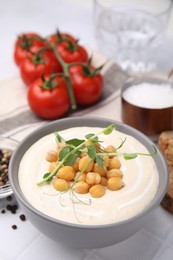Photo of Tasty chickpea soup in bowl on white tiled table