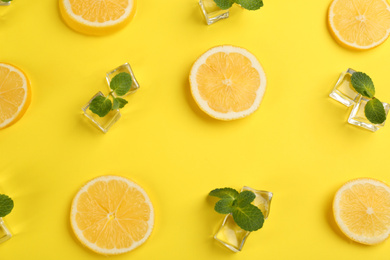 Photo of Lemonade layout with juicy lemon slices, ice and mint on yellow background, top view