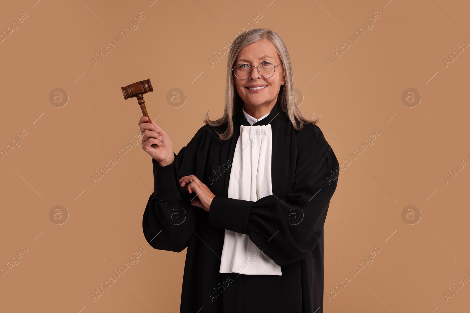 Photo of Smiling senior judge with gavel on light brown background