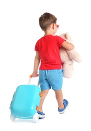 Photo of Cute little boy with toy and blue suitcase on white background