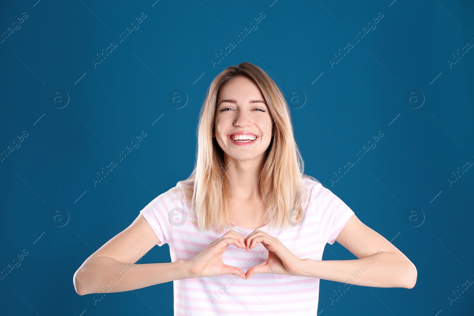 Photo of Portrait of pretty woman making heart with her hands on color background