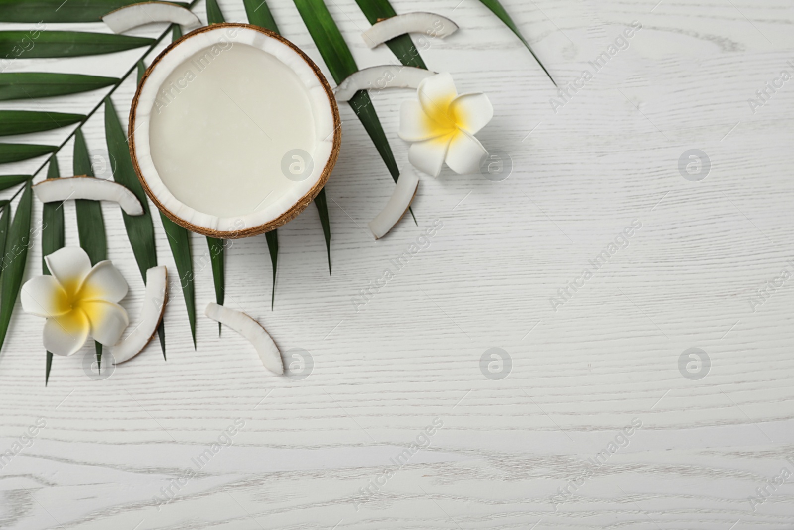 Photo of Flat lay composition with half of coconut on white wooden background. Space for text