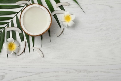 Flat lay composition with half of coconut on white wooden background. Space for text