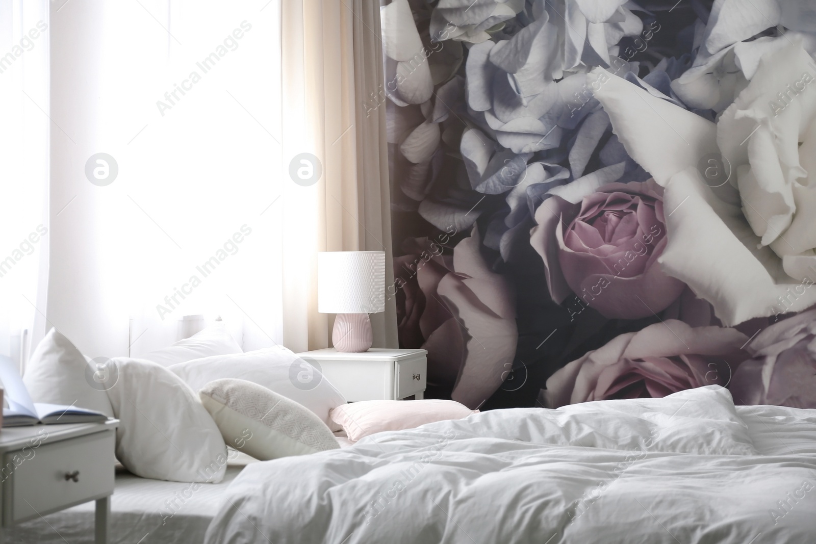 Photo of Comfortable bed near wall with floral wallpaper. Stylish room interior