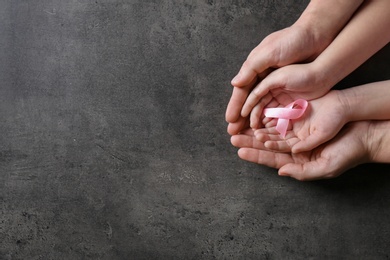 Woman and girl holding pink ribbon on grey background, top view with space for text. Breast cancer awareness