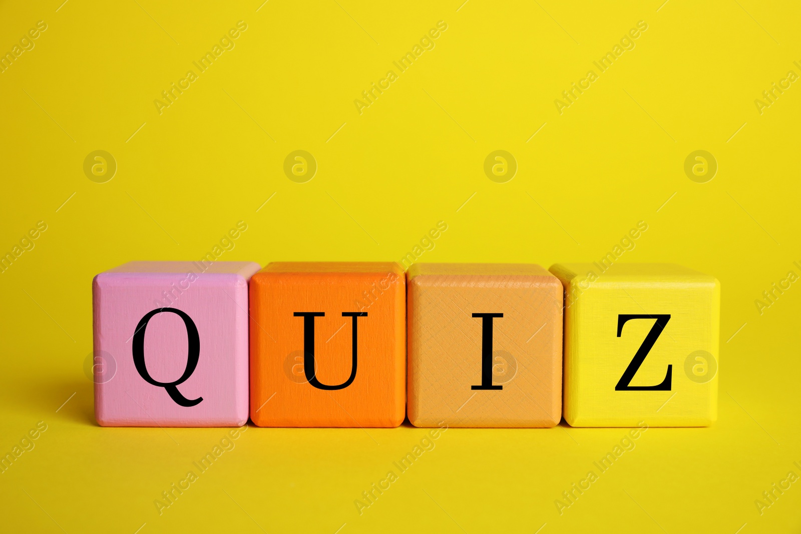 Photo of Colorful cubes with word Quiz on yellow background. Space for text