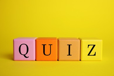 Photo of Colorful cubes with word Quiz on yellow background. Space for text