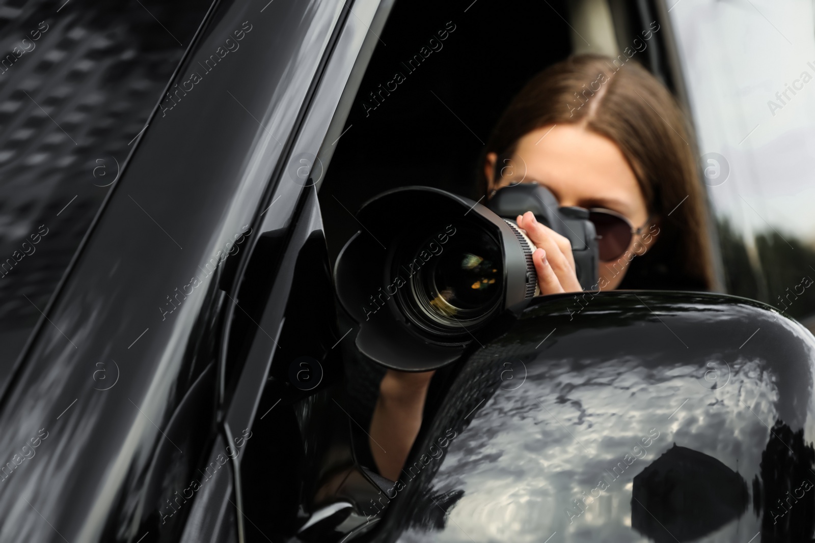 Photo of Private detective with camera spying from car, focus on lens
