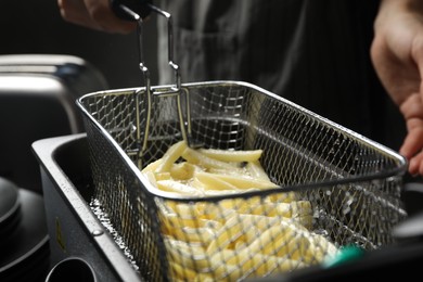 Chef cooking delicious french fries in hot oil, closeup