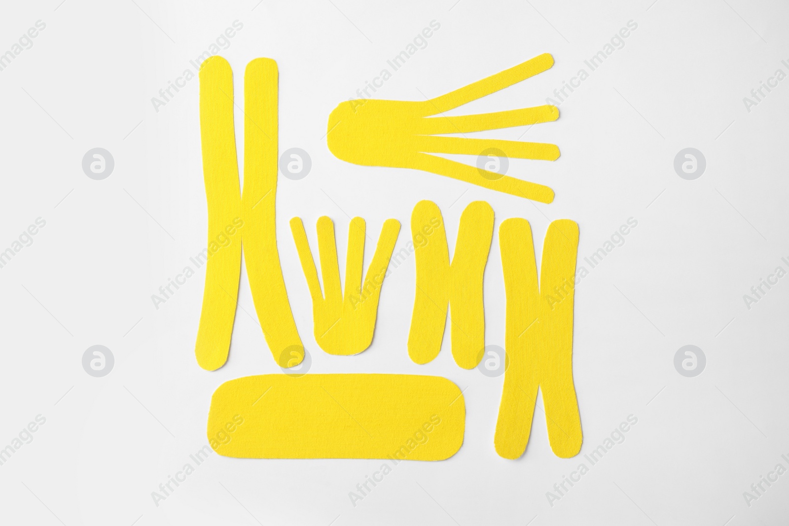 Photo of Yellow kinesio tape pieces on white background, top view