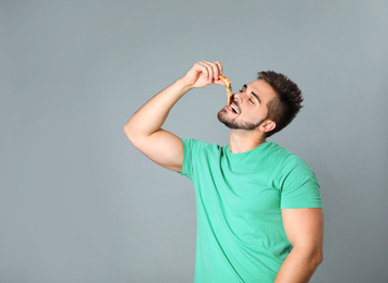 Photo of Handsome man eating pizza on grey background, space for text