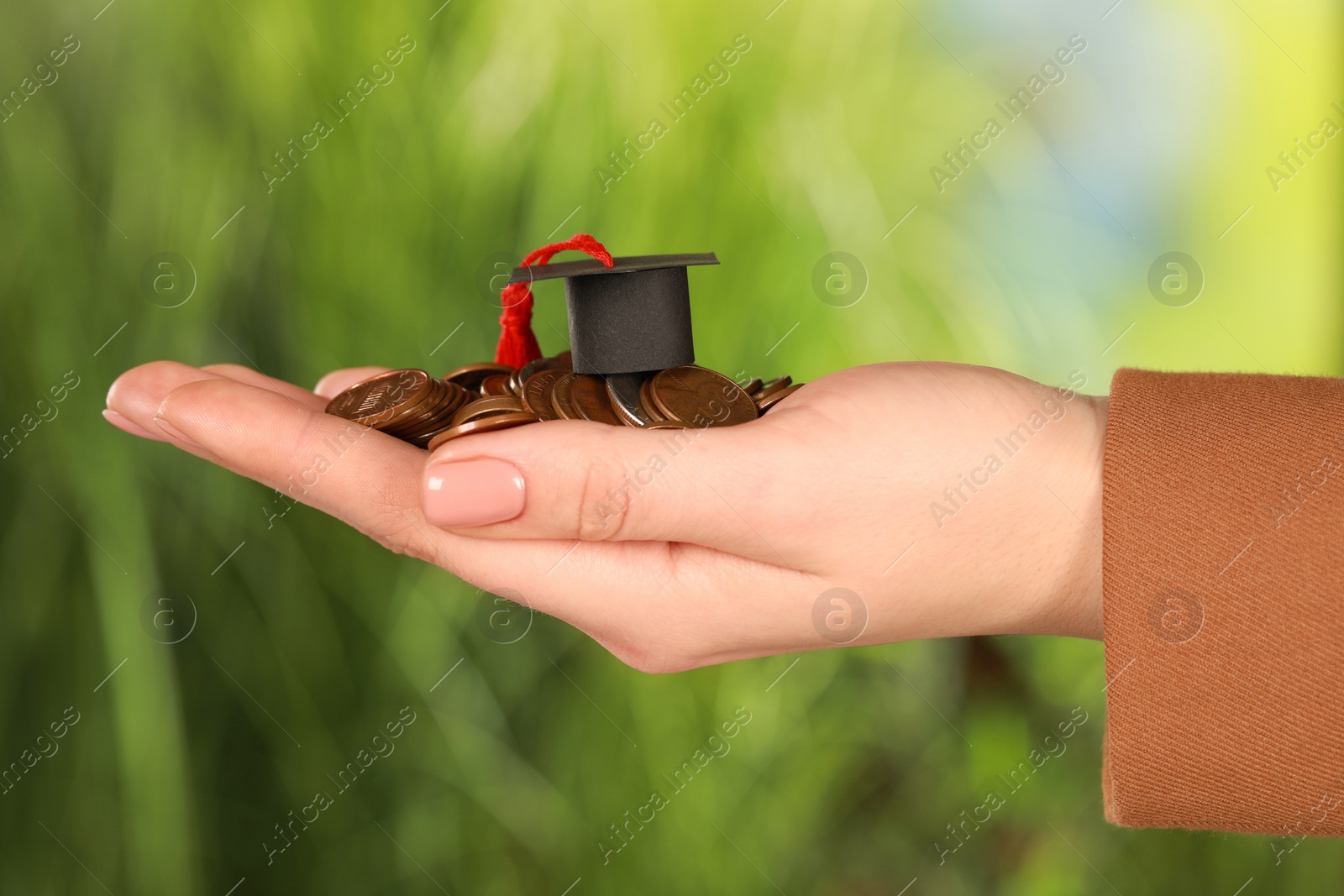 Photo of Woman holding coins and graduation cap against blurred background, closeup. Scholarship concept