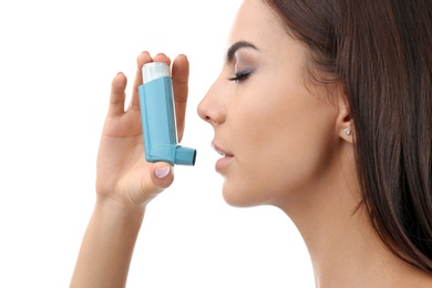 Photo of Young woman using asthma inhaler on white background