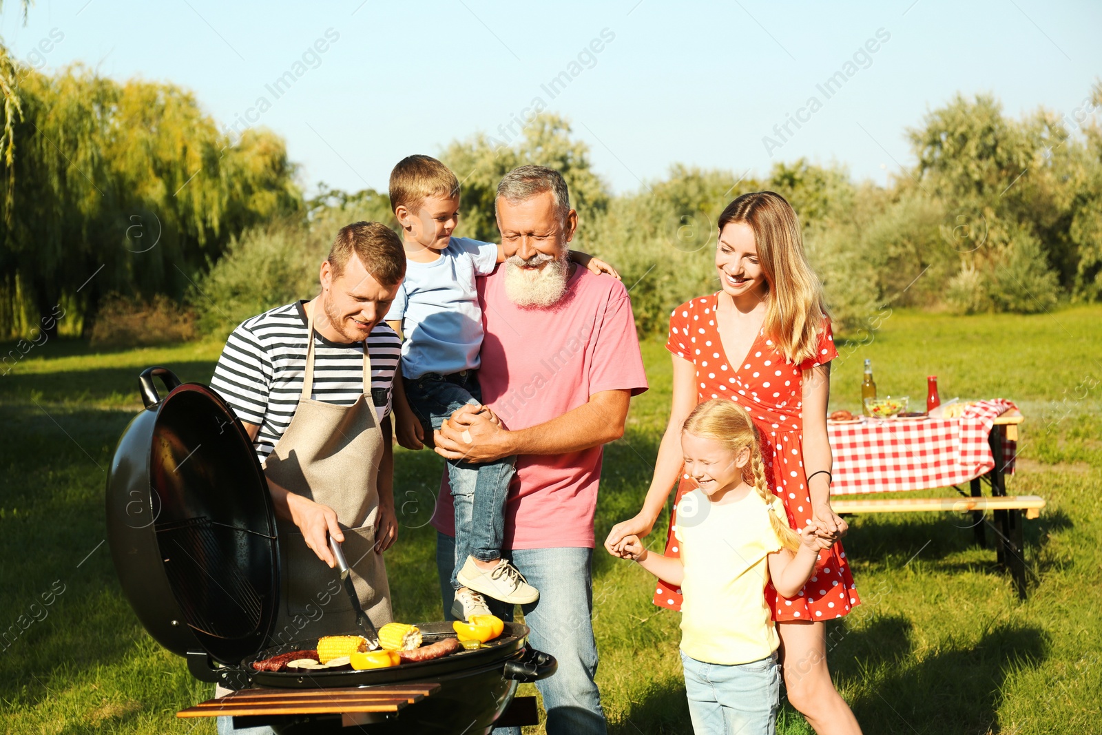 Photo of Happy family having barbecue in park on sunny day