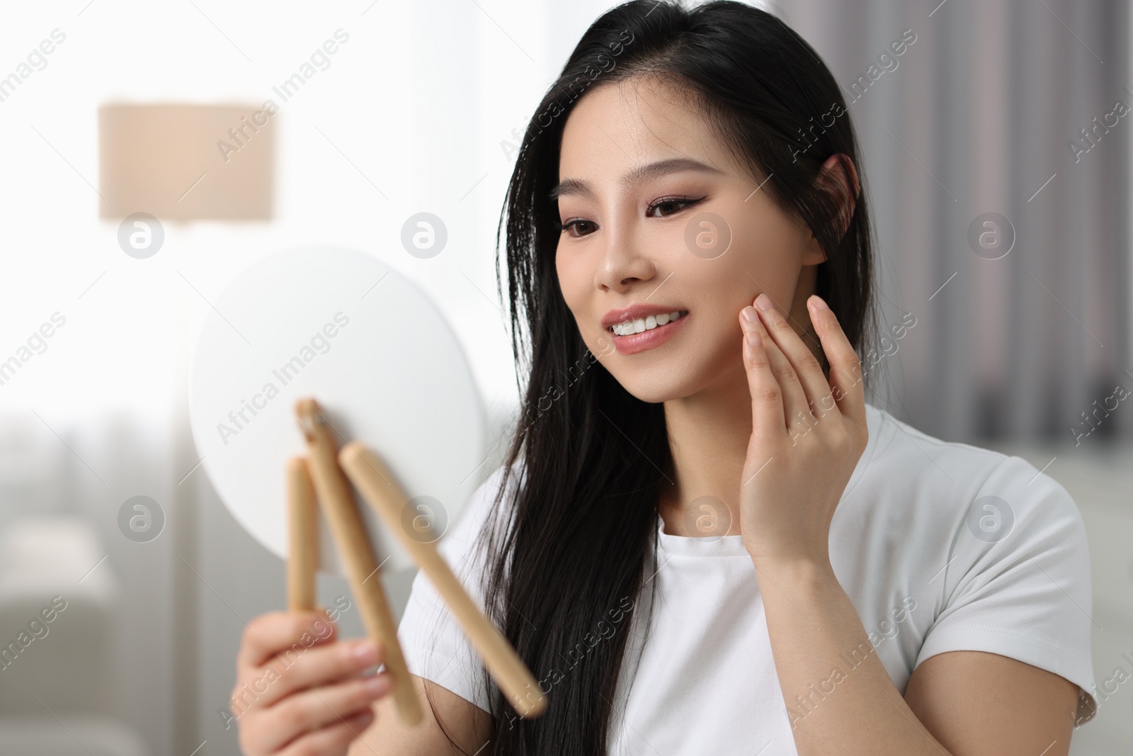 Photo of Woman with perfect skin looking at mirror indoors