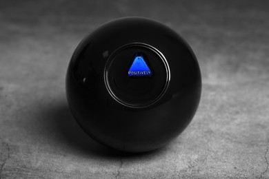 Magic eight ball with prediction Positively on grey table