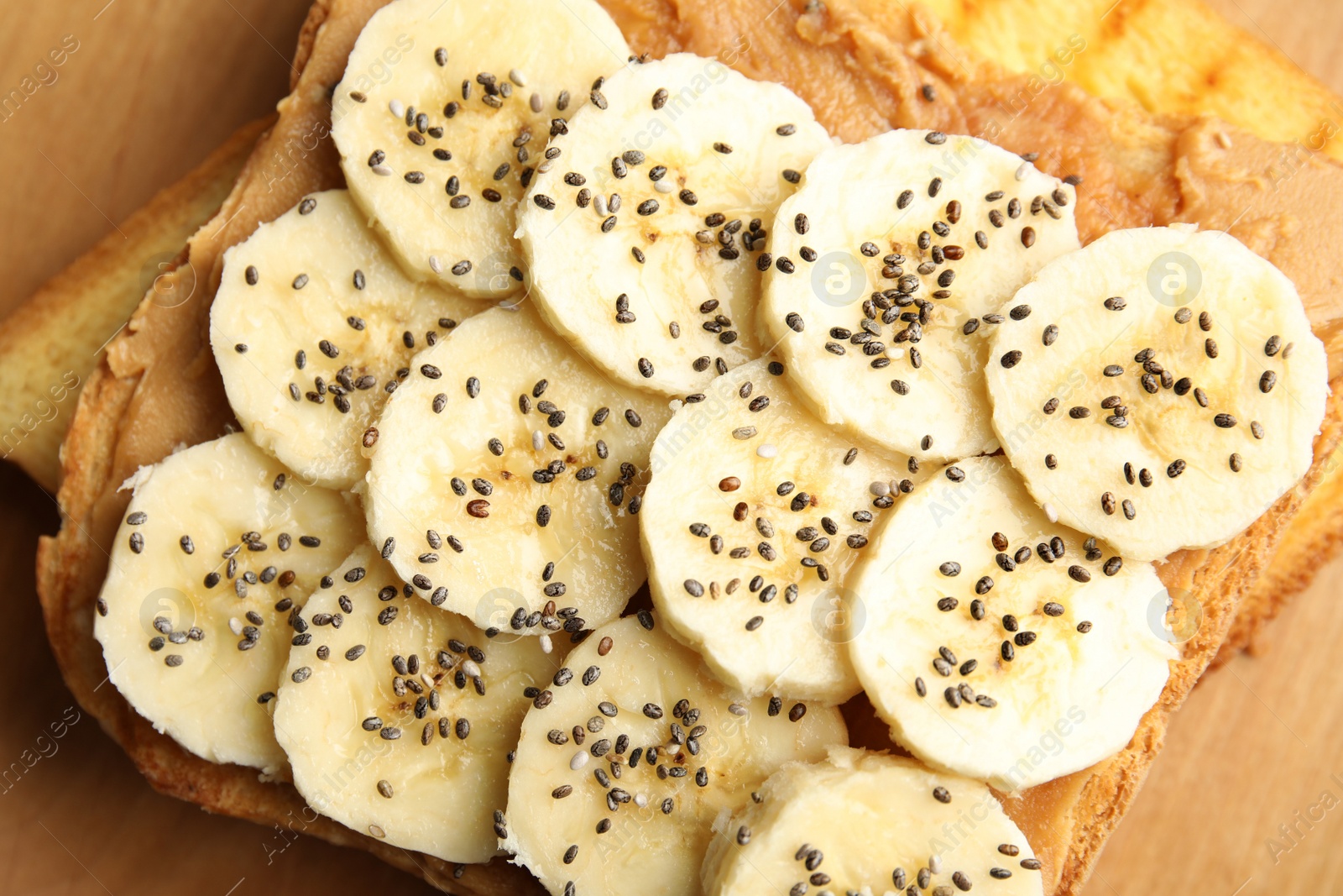 Photo of Tasty toast with banana, peanut butter and chia seeds, closeup