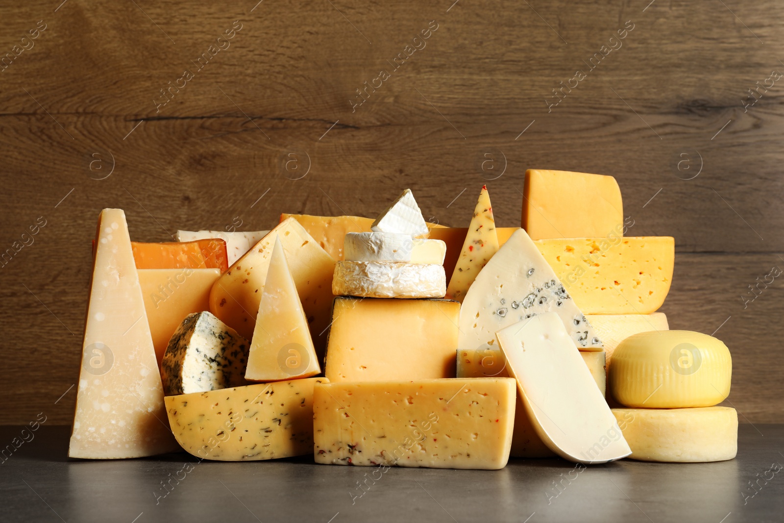 Photo of Different types of delicious cheese on table against wooden background