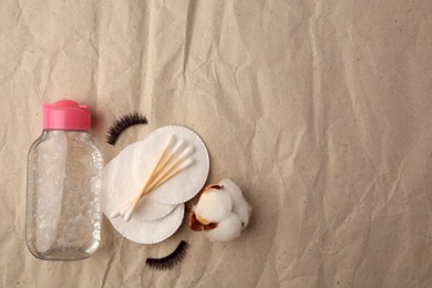 Photo of Flat lay composition with makeup remover and cotton flower on crumpled paper, space for text