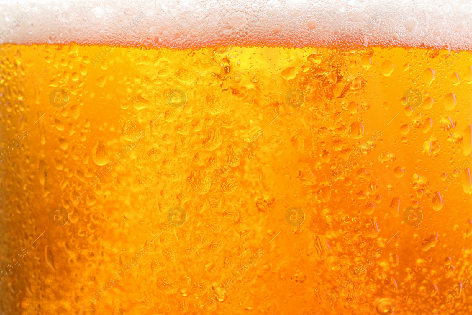 Photo of Glass of tasty cold beer with foam and condensation drops as background, closeup