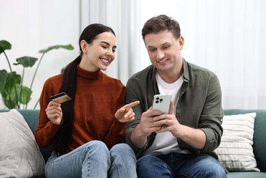 Photo of Happy couple with smartphone and credit card shopping online together at home